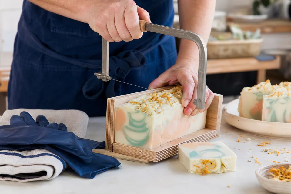 Fresh handmade soap loaf being cut into pastel swirled bars